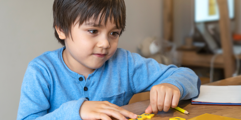 Young-student-assorting-letter-tiles-during-English-tuition-lesson-with-tutor